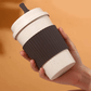 somebody holding a brown reuseable coffee cup